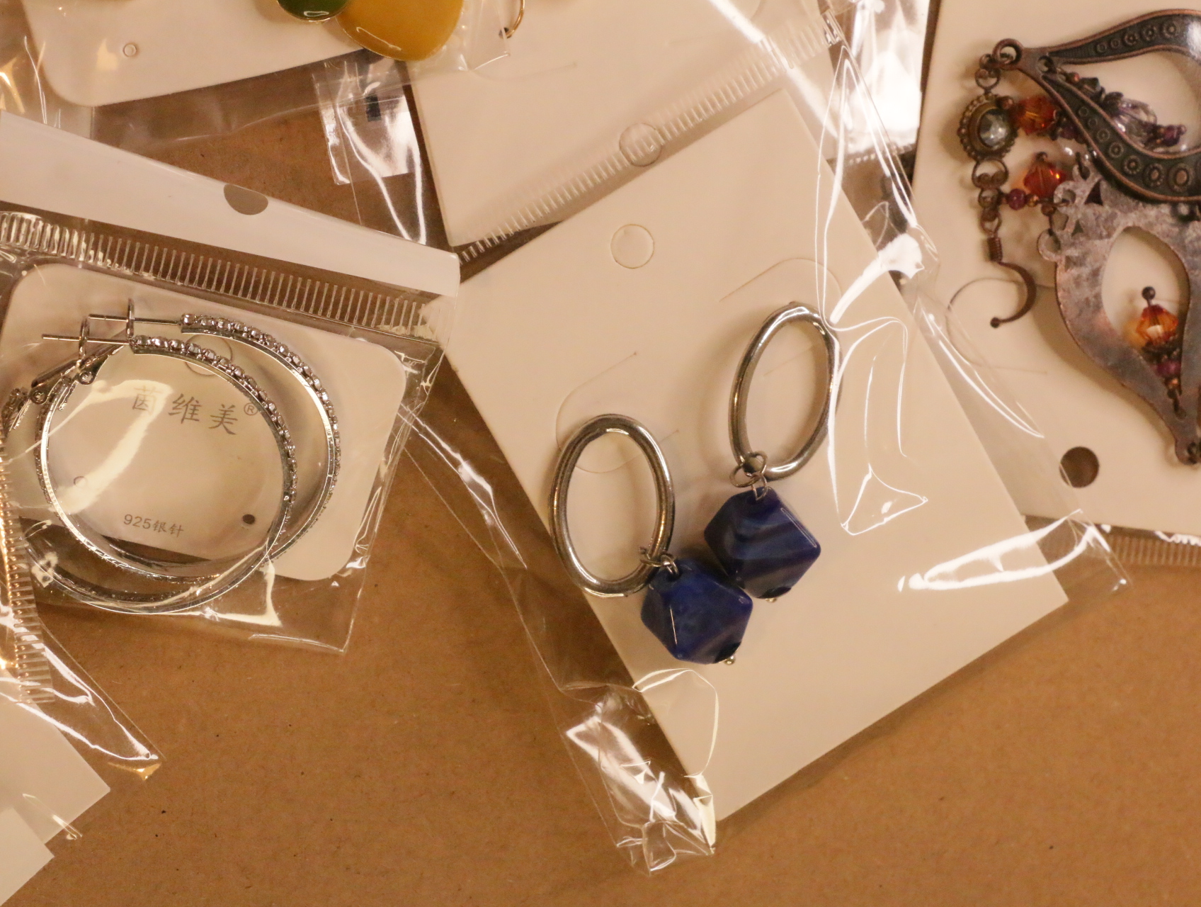 Pendientes ovalados colgantes con cuentas azules junto a aros plateados — lote de bisutería originales, detalle del acabado · Lola y Sol (LT041)