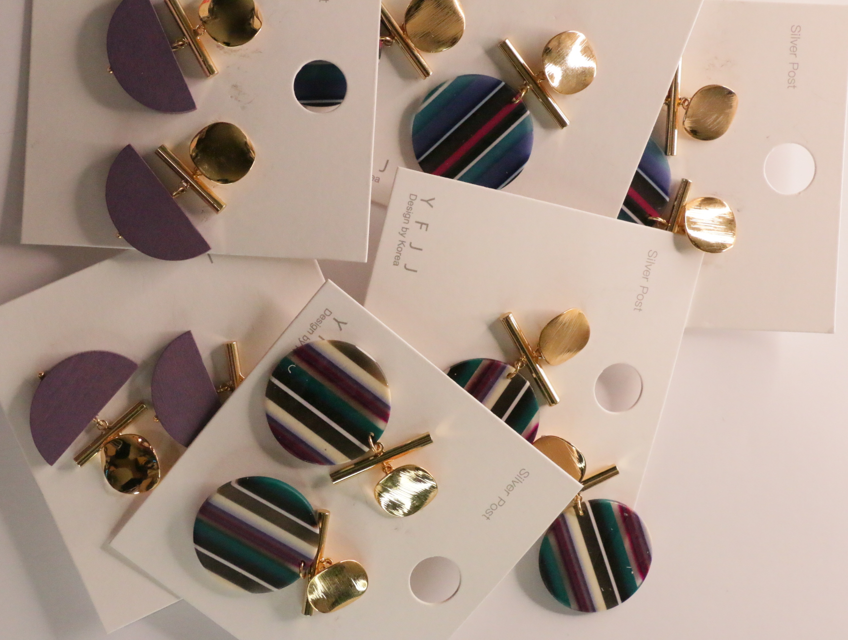 Pendientes geométricos sobre tarjetas superpuestas — lote de bisutería originales, detalle del acabado · Lola y Sol (LT043)