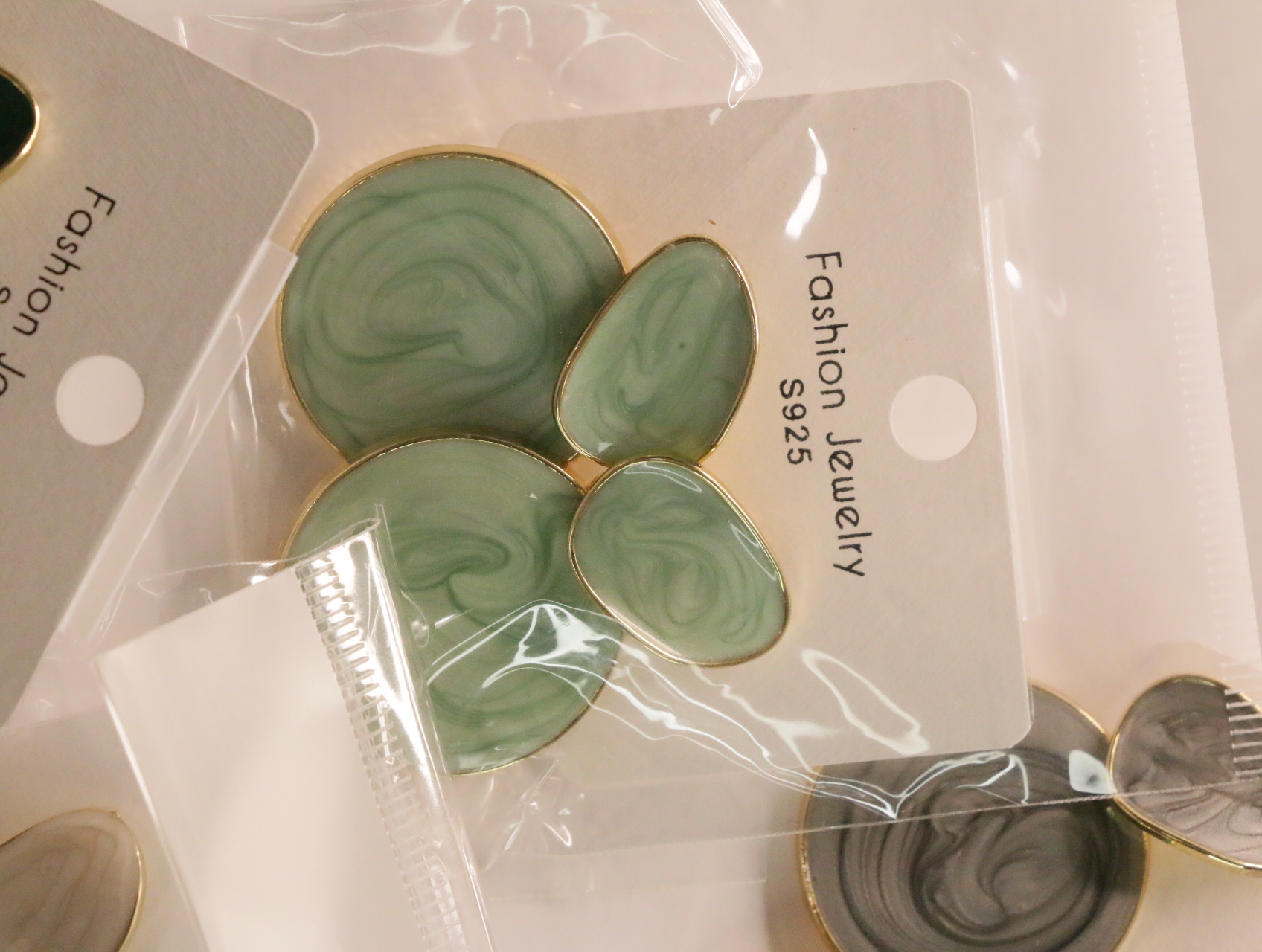 Pendientes colgantes marmoleados verde claro sobre tarjeta — lote de bisutería de moda, vista lateral · Lola y Sol (LT044)