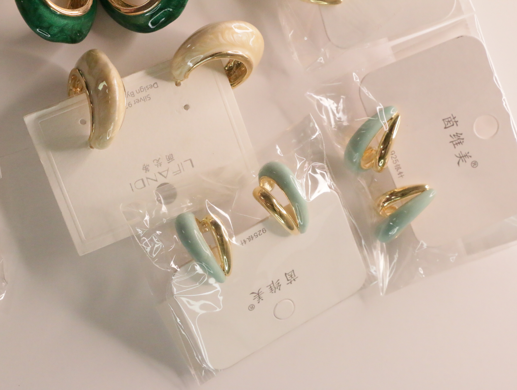 Pendientes verde menta y crema sobre sus soportes — lote de bisutería dorados, primer plano · Lola y Sol (LT045)