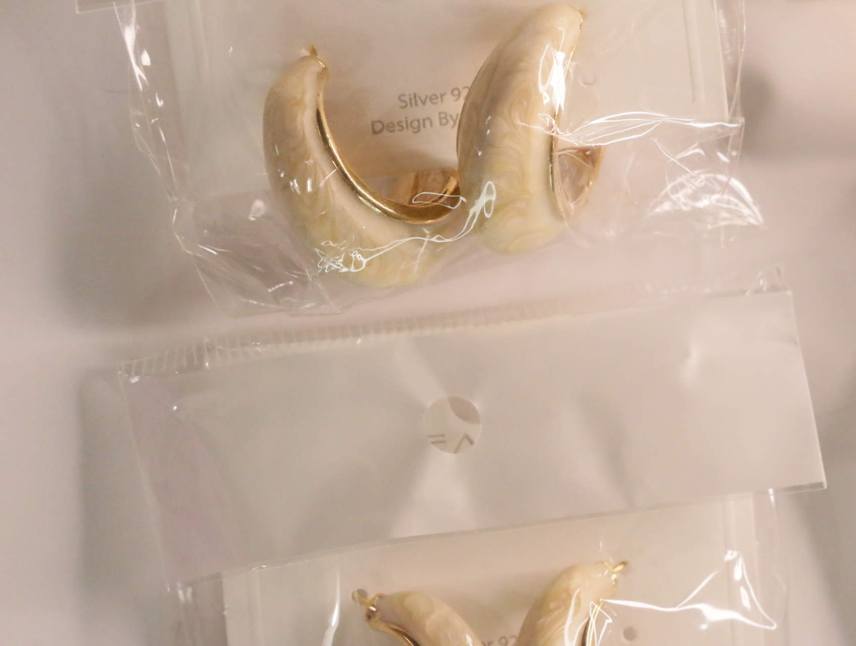 Pendientes de aro crema jaspeado en envoltorio transparente — lote de bisutería originales, detalle del acabado · Lola y Sol (LT045)