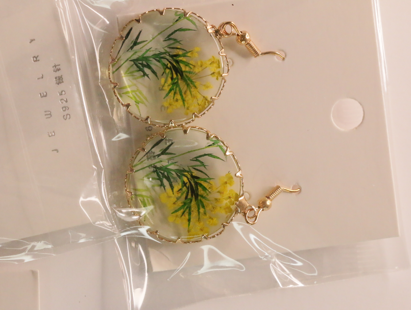 Pendientes redondos transparentes con flores amarillas y follaje verde — lote de bisutería dorados, primer plano · Lola y Sol (LT046)