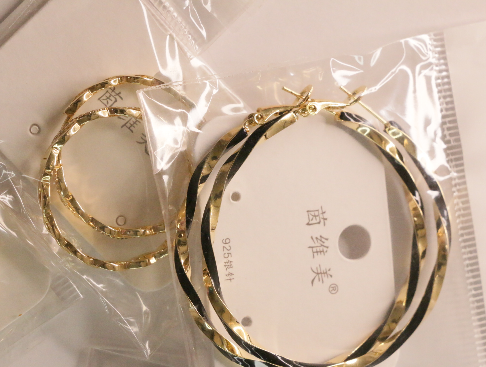 Pendientes de aro retorcidos en dorado con detalles negros — lote de bisutería de moda, vista lateral · Lola y Sol (LT047)
