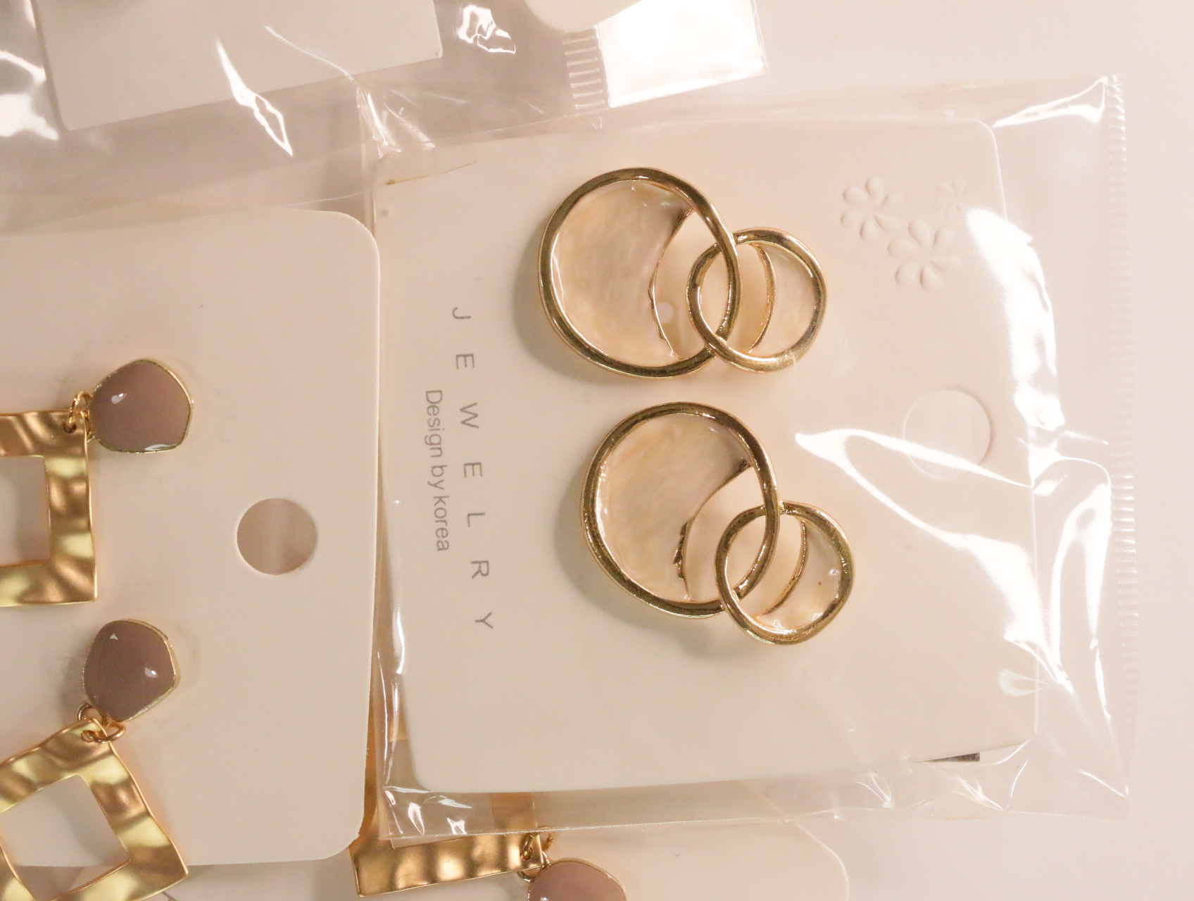 Pendientes de círculos enlazados dorados con detalles translúcidos claros — lote de bisutería de moda, vista lateral · Lola y Sol (LT049)