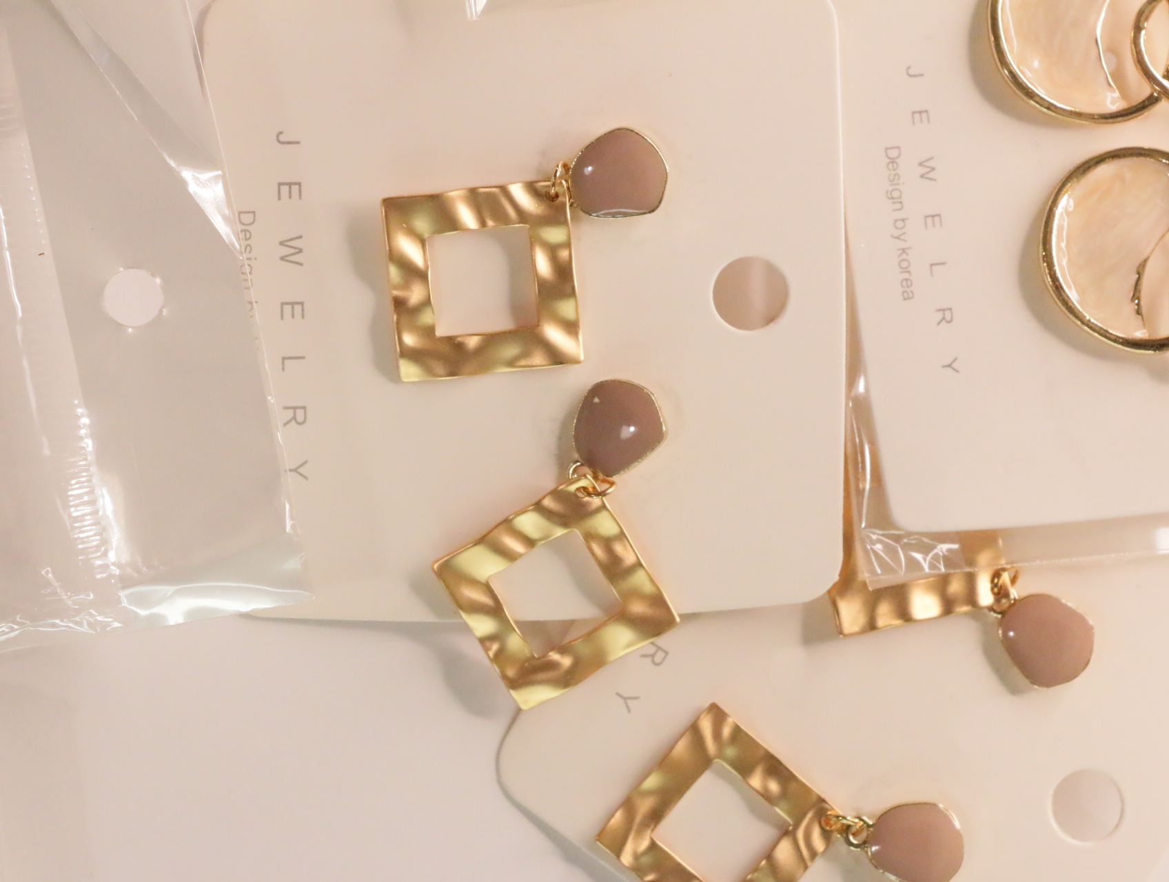 Pendientes colgantes geométricos dorados con detalles nude brillantes — lote de bisutería originales, detalle del acabado · Lola y Sol (LT049)