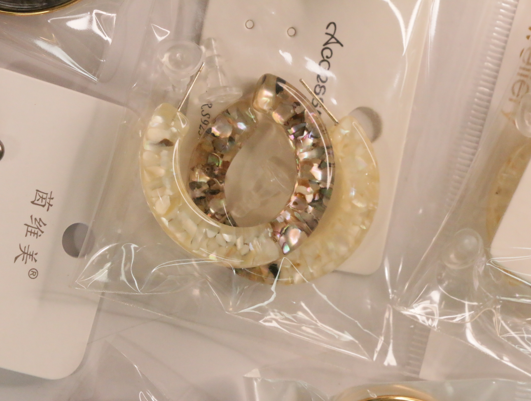 Pendientes de aro color crema con efectos decorativos nacarados — lote de bisutería originales, detalle del acabado · Lola y Sol (LT050)