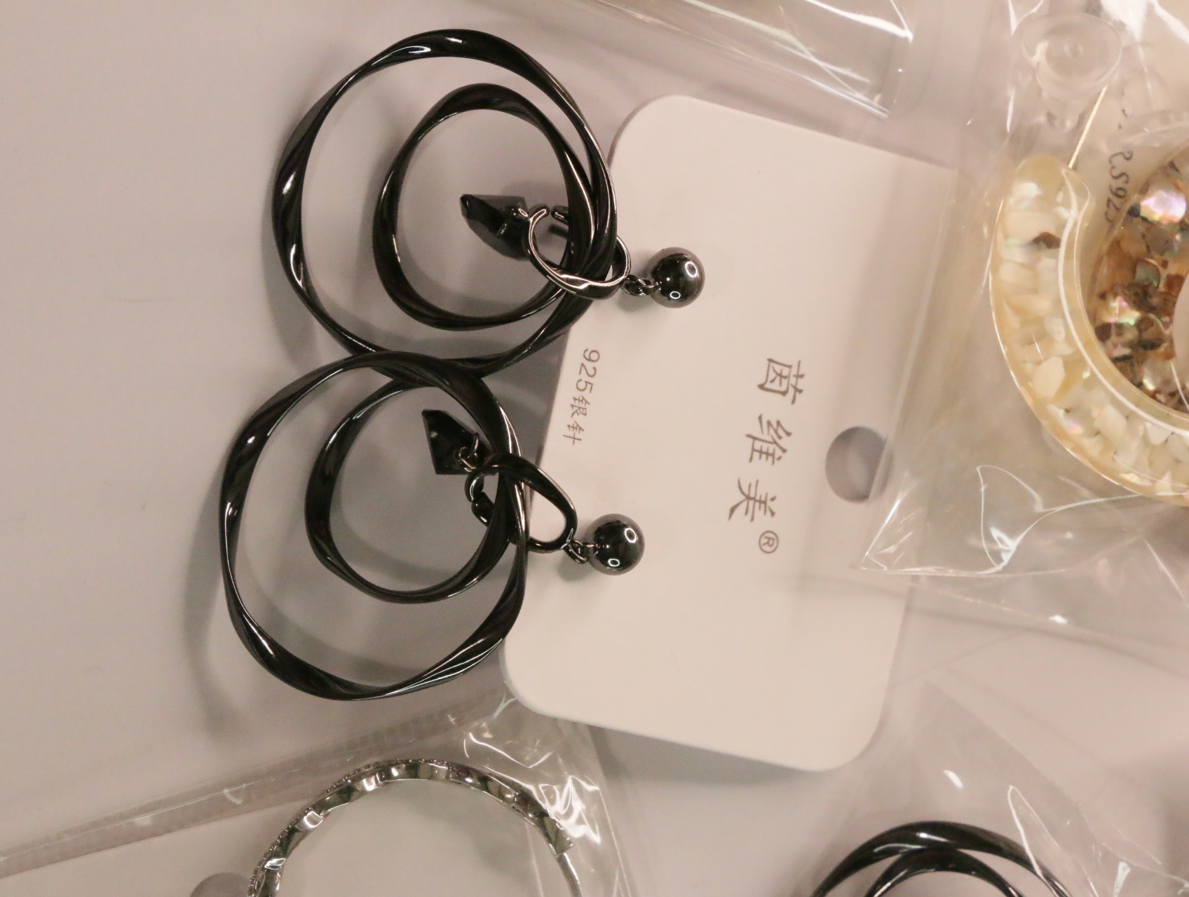 Pendientes colgantes negros brillantes con anillas entrelazadas — lote de bisutería online, vista principal · Lola y Sol (LT050)