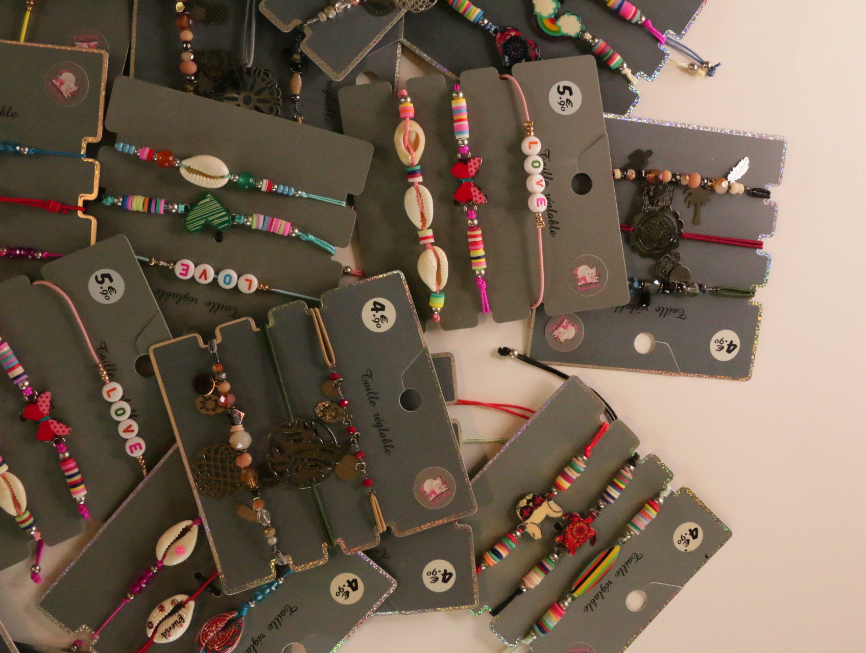 Detalle de pulseras con cuentas de letras y colgantes decorativos — lote de bisutería de moda, vista lateral · Lola y Sol (LT054)