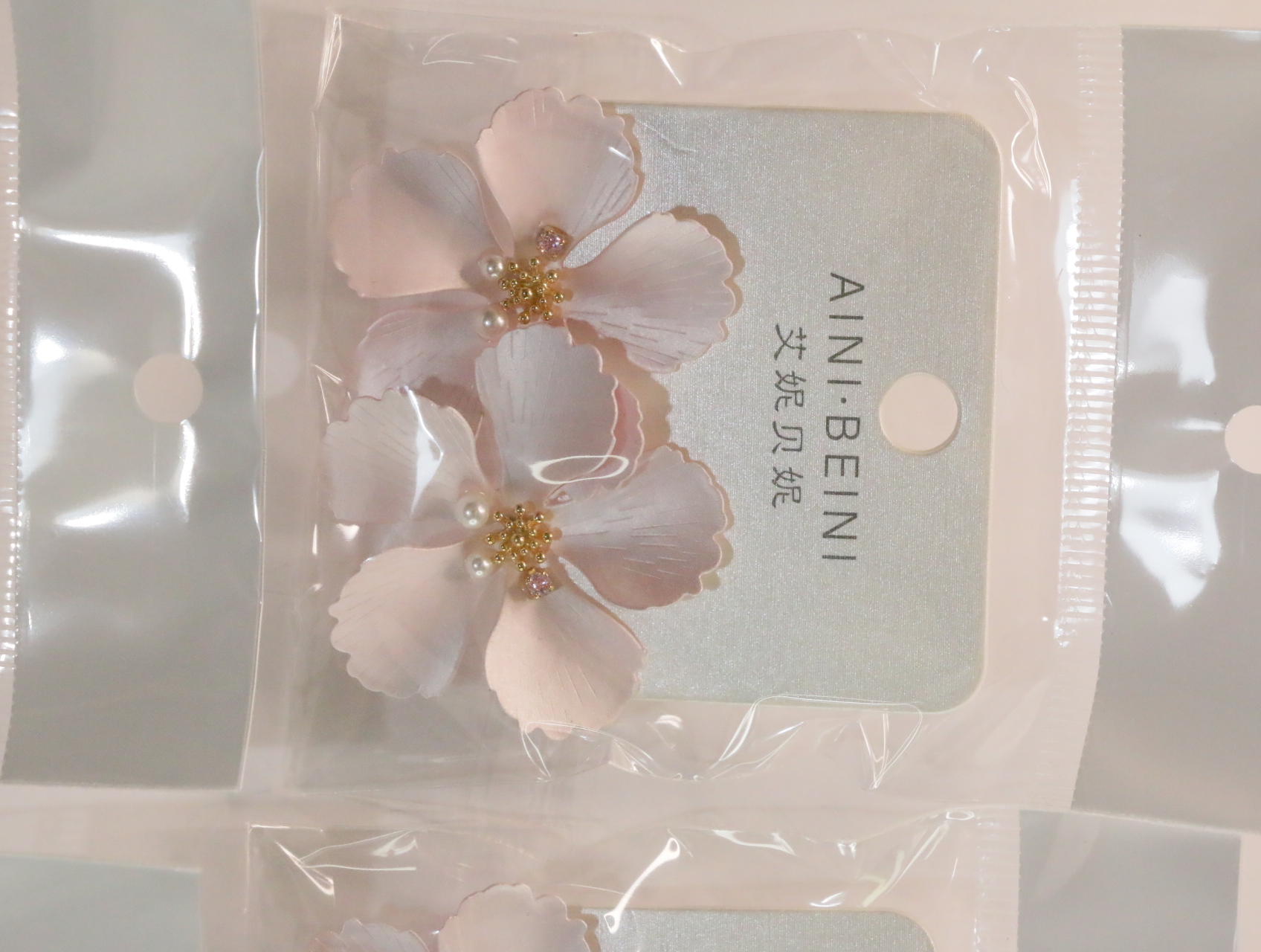 Pendientes de flores rosas con centros dorados sobre tarjeta — lote de bisutería dorados, primer plano · Lola y Sol (LT056)