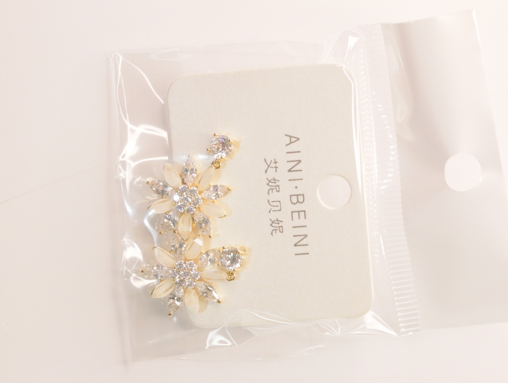 Pendientes florales con pétalos crema y detalles brillantes sobre tarjeta — lote de bisutería baratos, detalle · Lola y Sol (LT060)