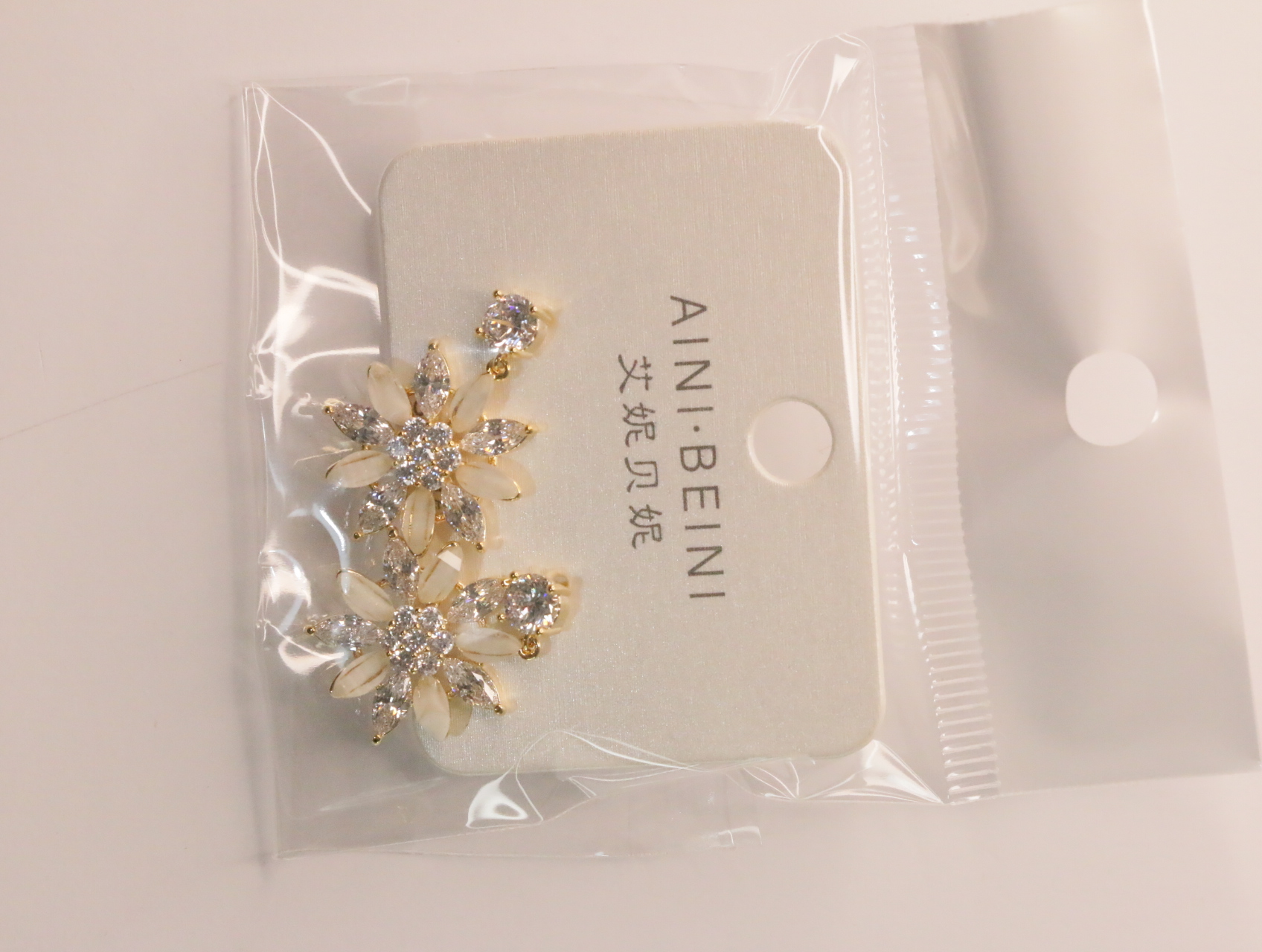 Detalle de pendientes florales dorados con adornos crema — lote de bisutería dorados, primer plano · Lola y Sol (LT060)