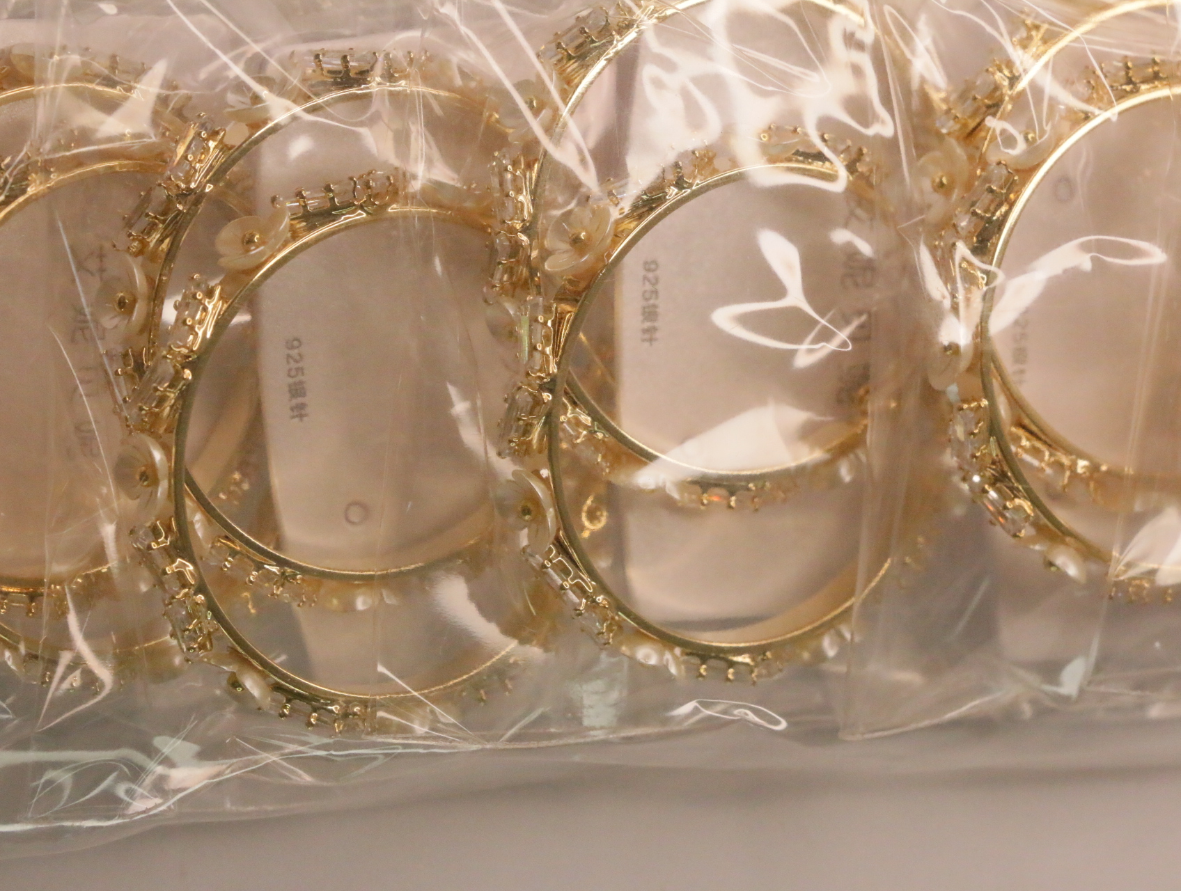 Detalle de aros dorados con adornos brillantes y efecto perla — lote de bisutería baratos, detalle · Lola y Sol (LT062)
