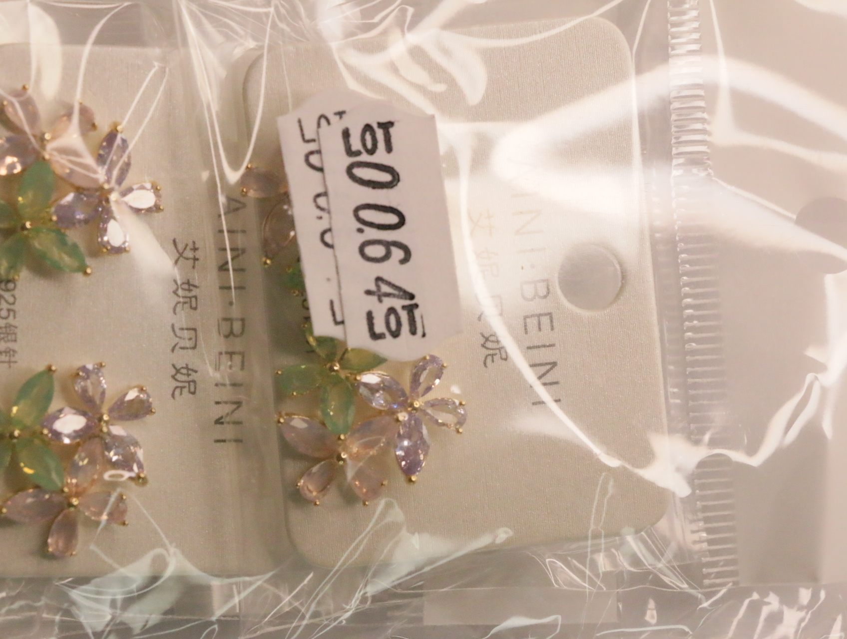 Pendientes florales en su envoltorio con etiqueta de referencia interna — lote de bisutería de moda, vista lateral · Lola y Sol (LT064)