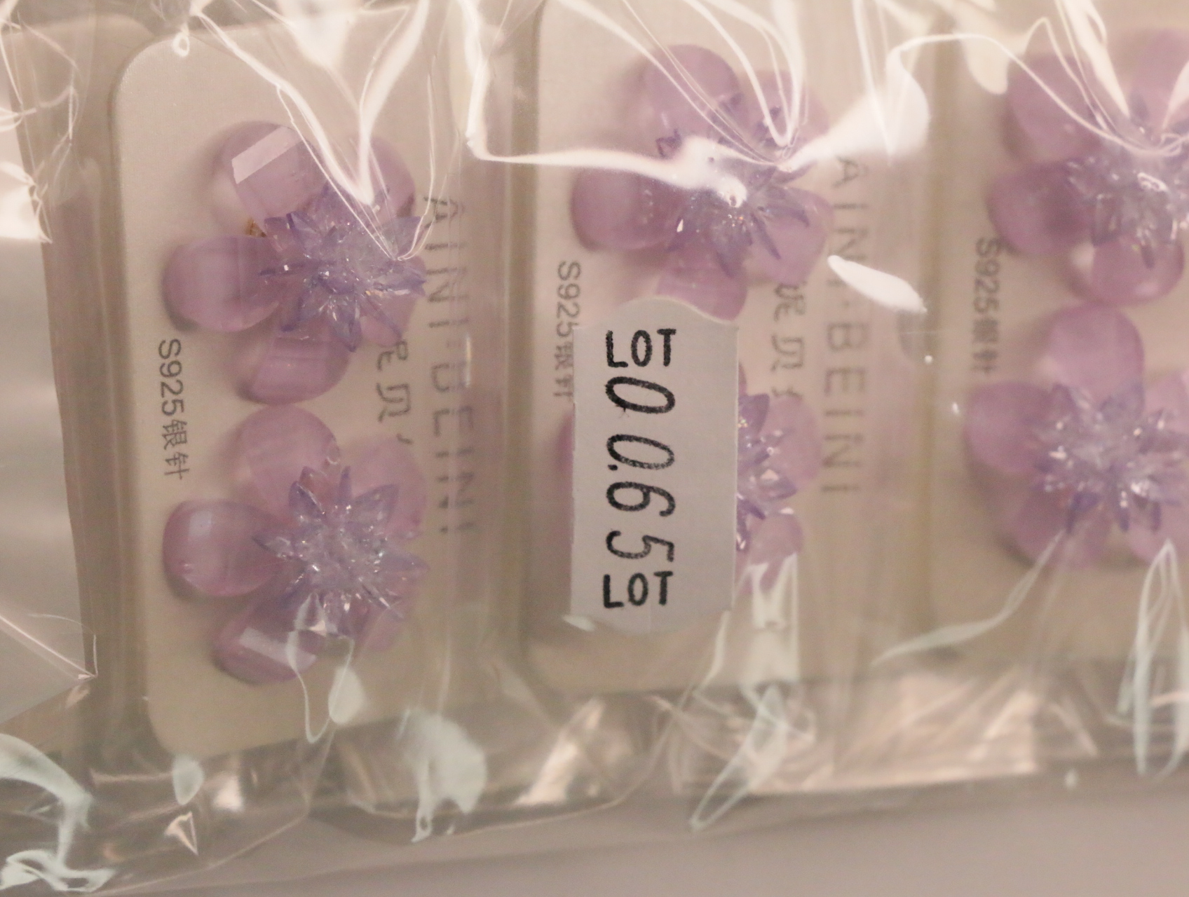 Pendientes de flor lila con etiqueta de referencia interna — lote de bisutería de moda, vista lateral · Lola y Sol (LT065)
