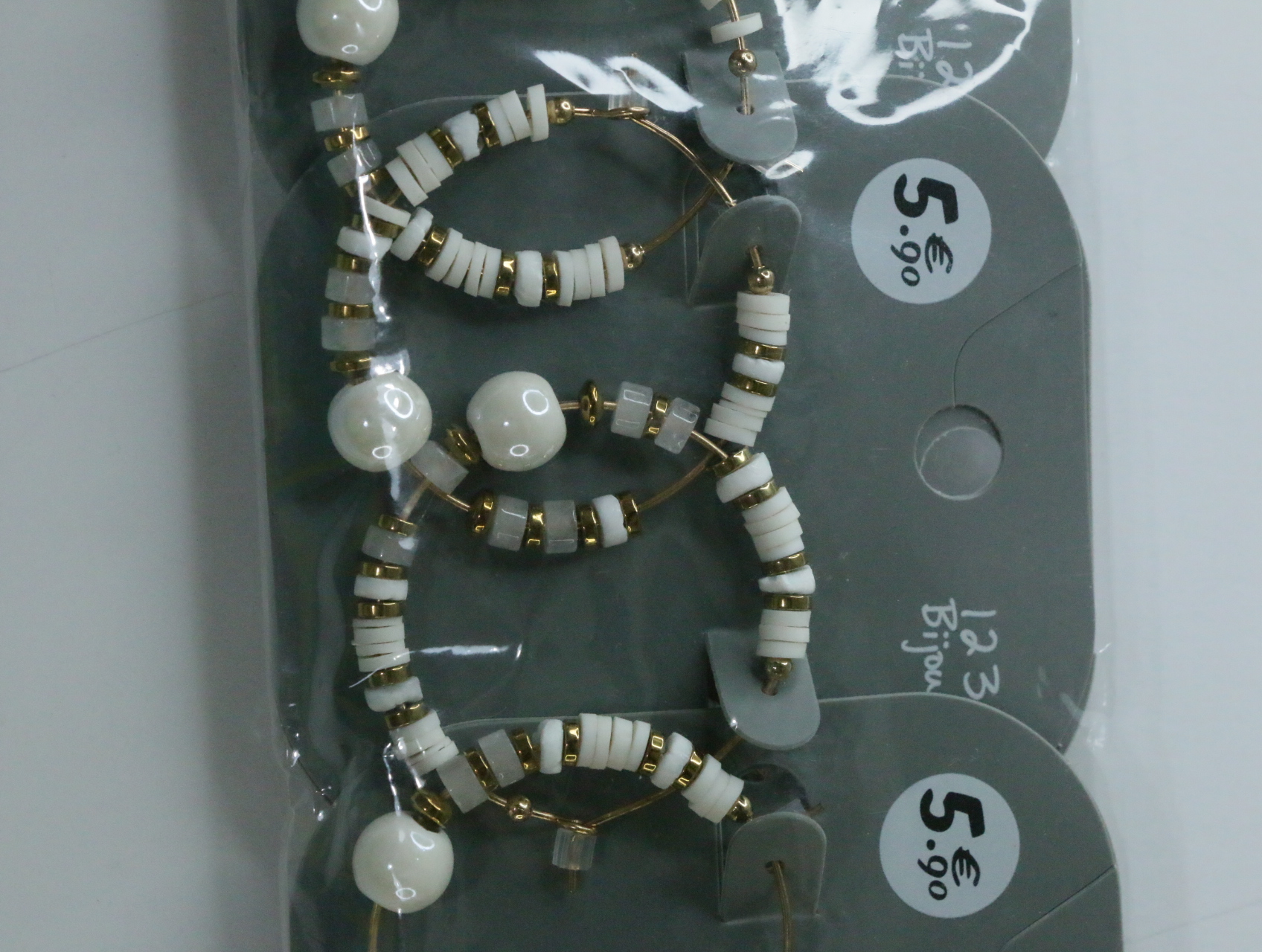 Detalle de los aros con cuentas blancas y detalles dorados — lote de bisutería dorados, primer plano · Lola y Sol (LT068)