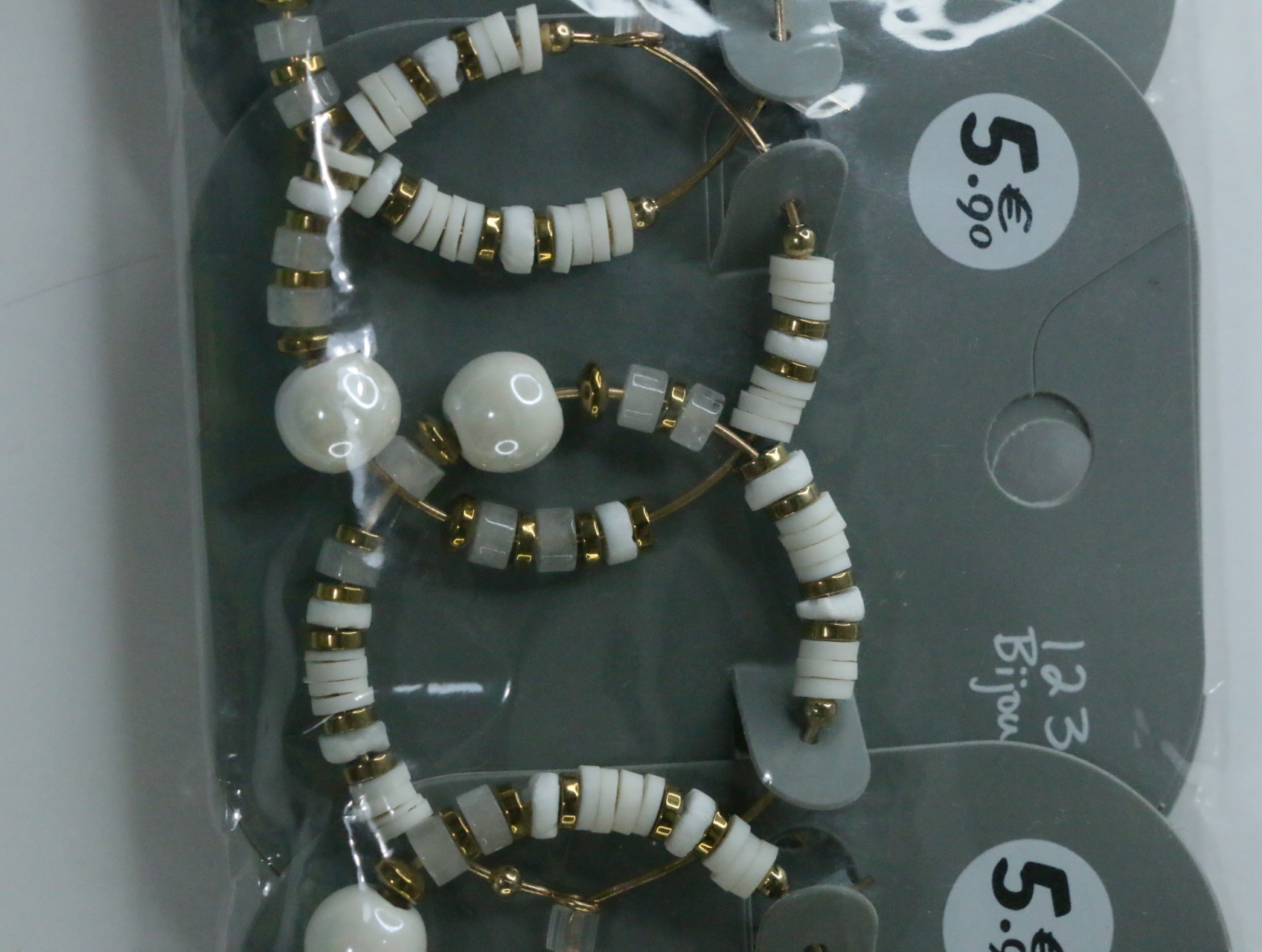 Detalle de cuentas blancas y translúcidas en los aros dorados — lote de bisutería de moda, vista lateral · Lola y Sol (LT068)
