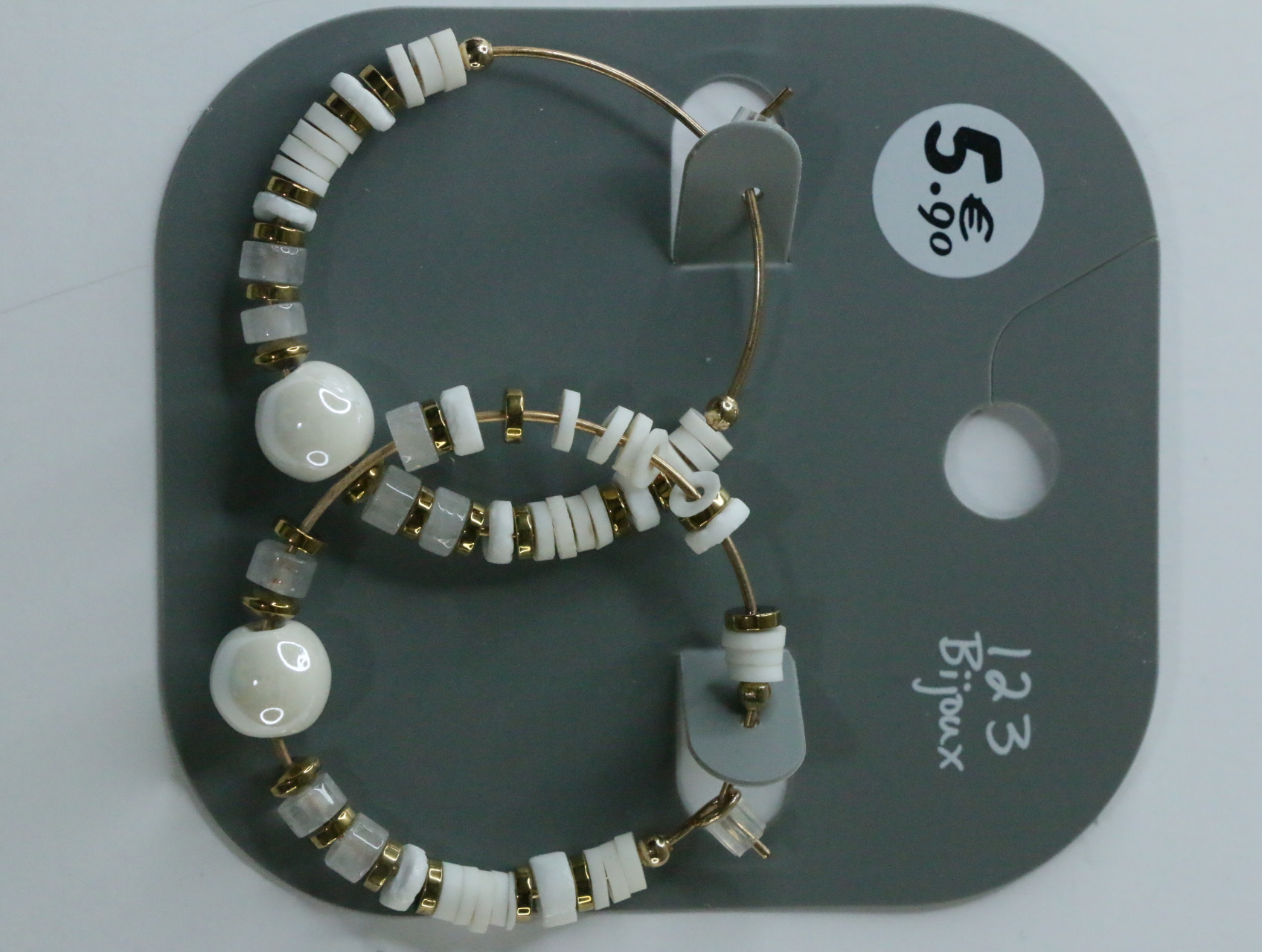 Pendientes de aro dorados con cuentas blancas sobre tarjeta — lote de bisutería originales, detalle del acabado · Lola y Sol (LT068)