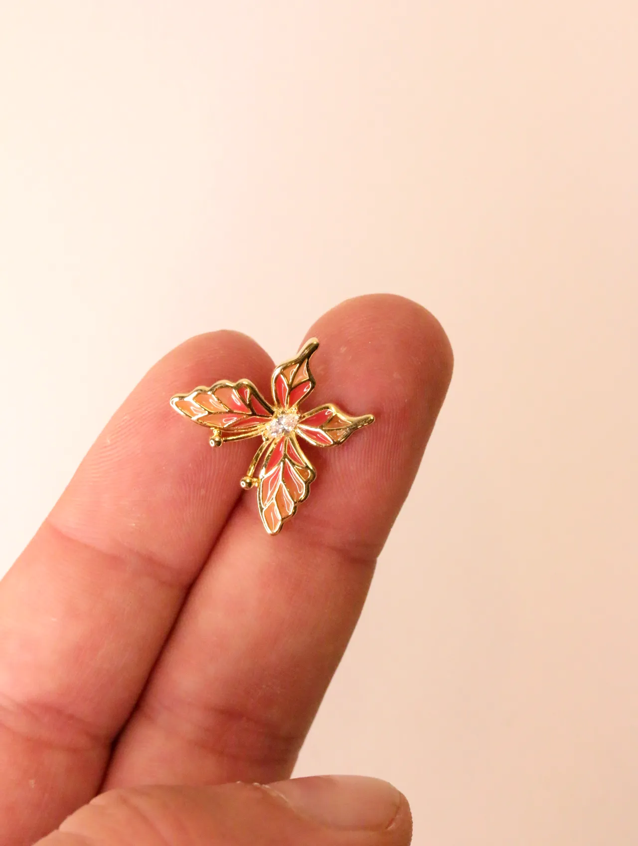 Primer plano de un pendiente de mariposa en un dedo, mostrando detalles de esmalte y cristal. — pendientes baratos, detalle · Lola y Sol (PO-PD-43)